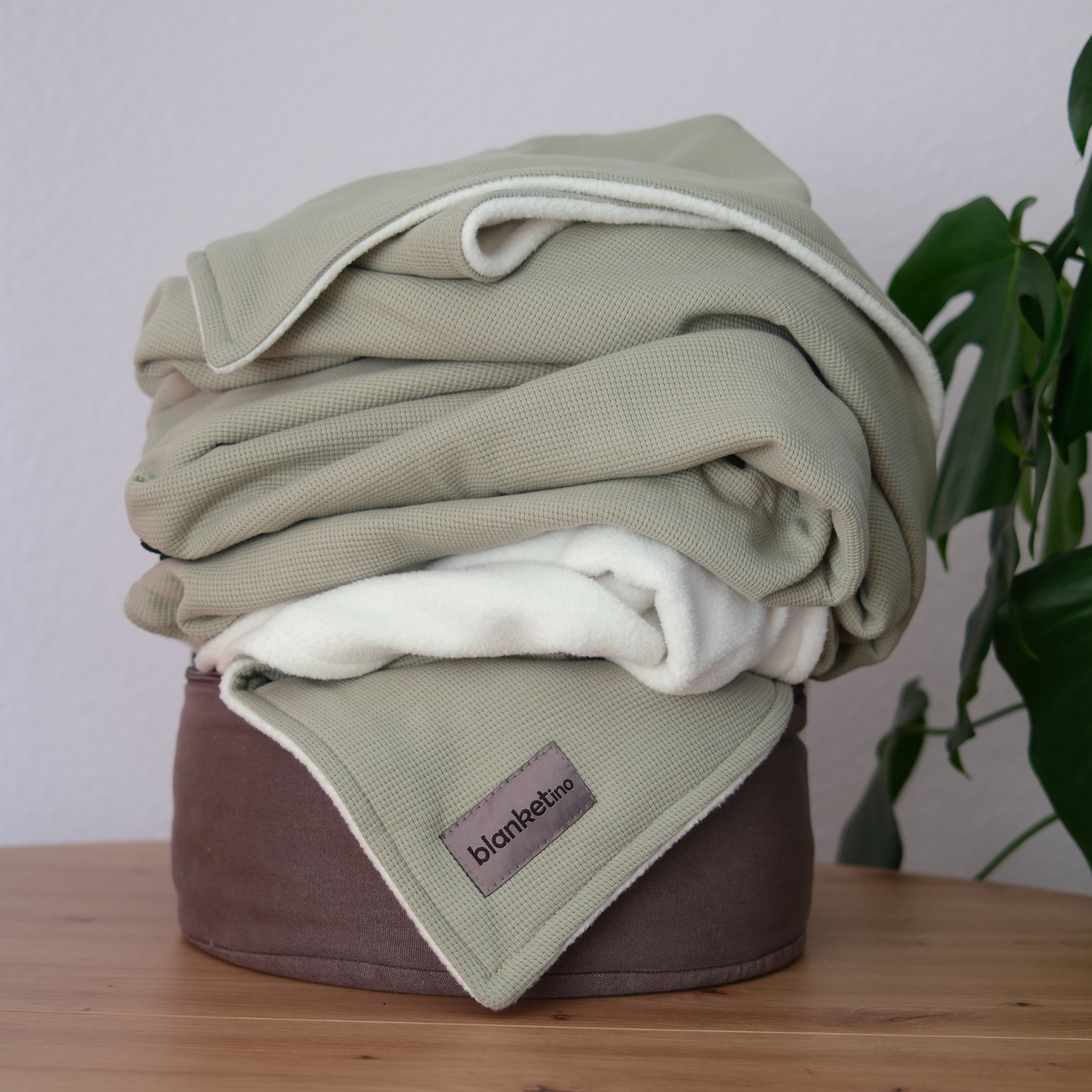 Kuscheldecke aus 100 % Baumwolle in Salbeigrün, Sommerdecke, gefaltet auf einem Pouf, ideal für gemütliche Stunden.
