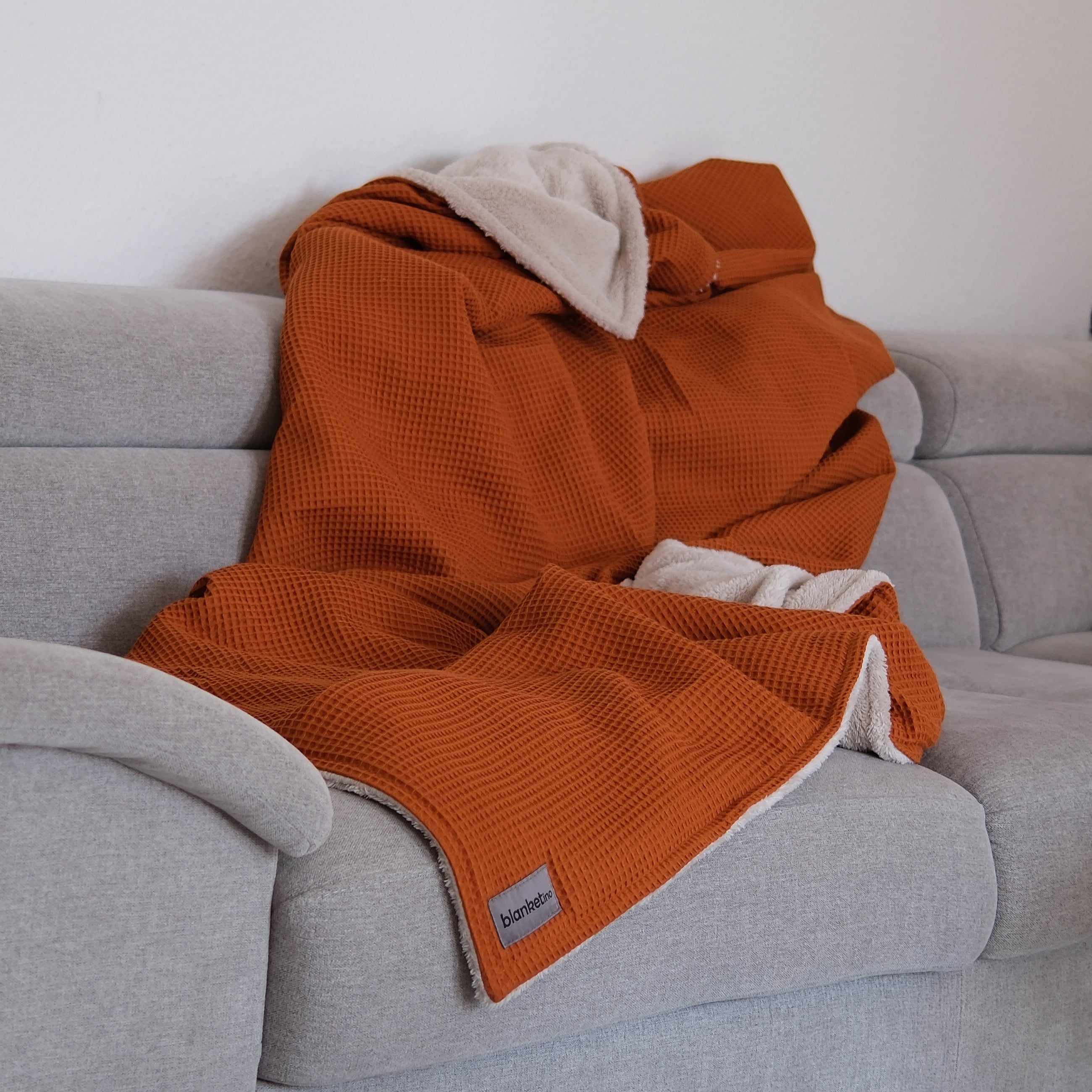 Kuscheldecke "Vollkommen" Cognac Beige – dekoriert auf einem Sofa