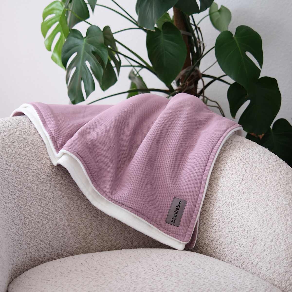 Sommerdecke aus 100% Baumwolle von blanketino.de in Beere, liegt über Sessel und Rückenlehne, weiche Textur sichtbar