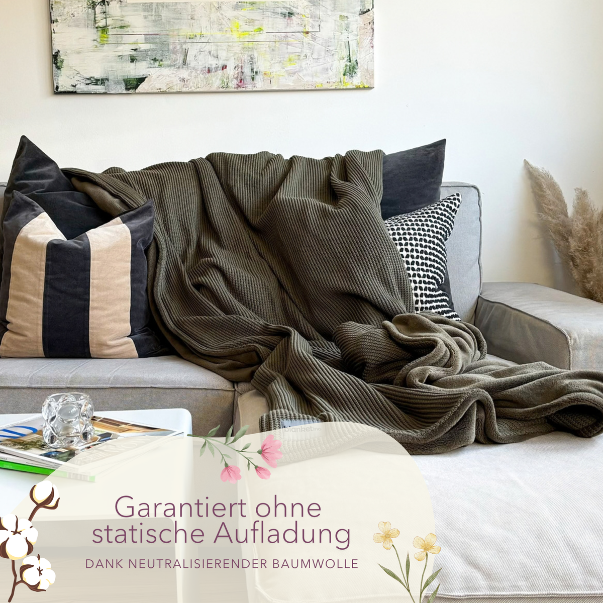 Dunkelgrüne Kuscheldecke aus Baumwollstrick von blanketino.de, perfekt für gemütliche Stunden auf einem grauen Sofa.