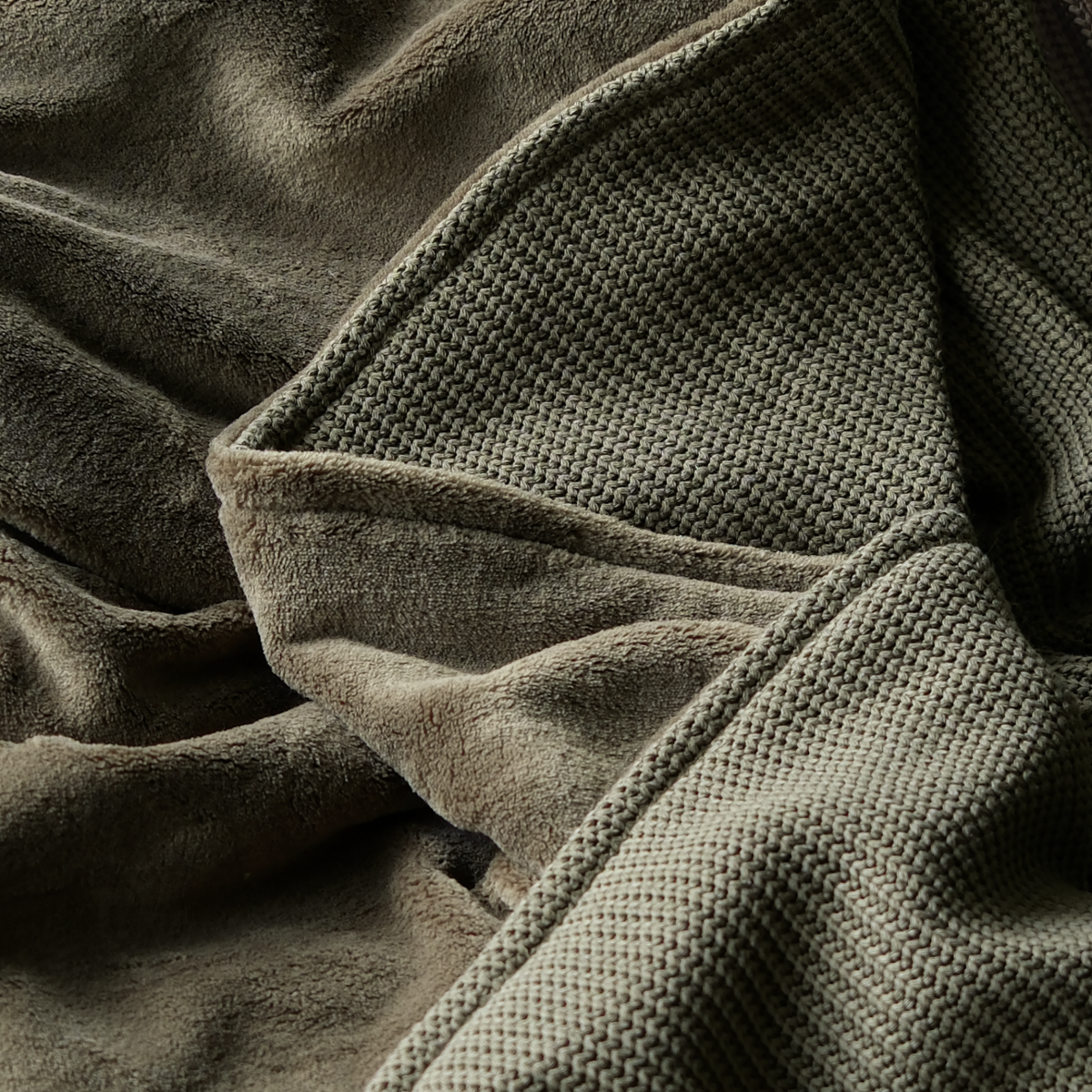 Dunkelgrüne Kuscheldecke aus Baumwollstrick von blanketino.de, weiche Strick- und Flauschinnenseite, perfekte Wohndecke.