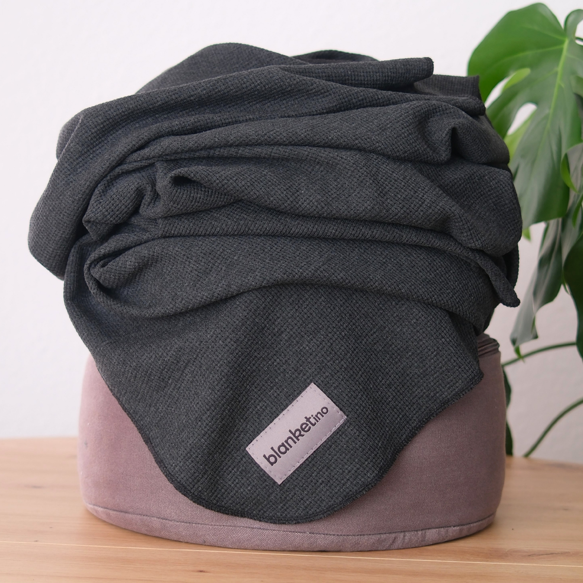 Leichte Baumwoll-Sommerdecke in Anthrazit, 150 x 210 cm, aus 100% Baumwolle, auf einem Pouf liegend