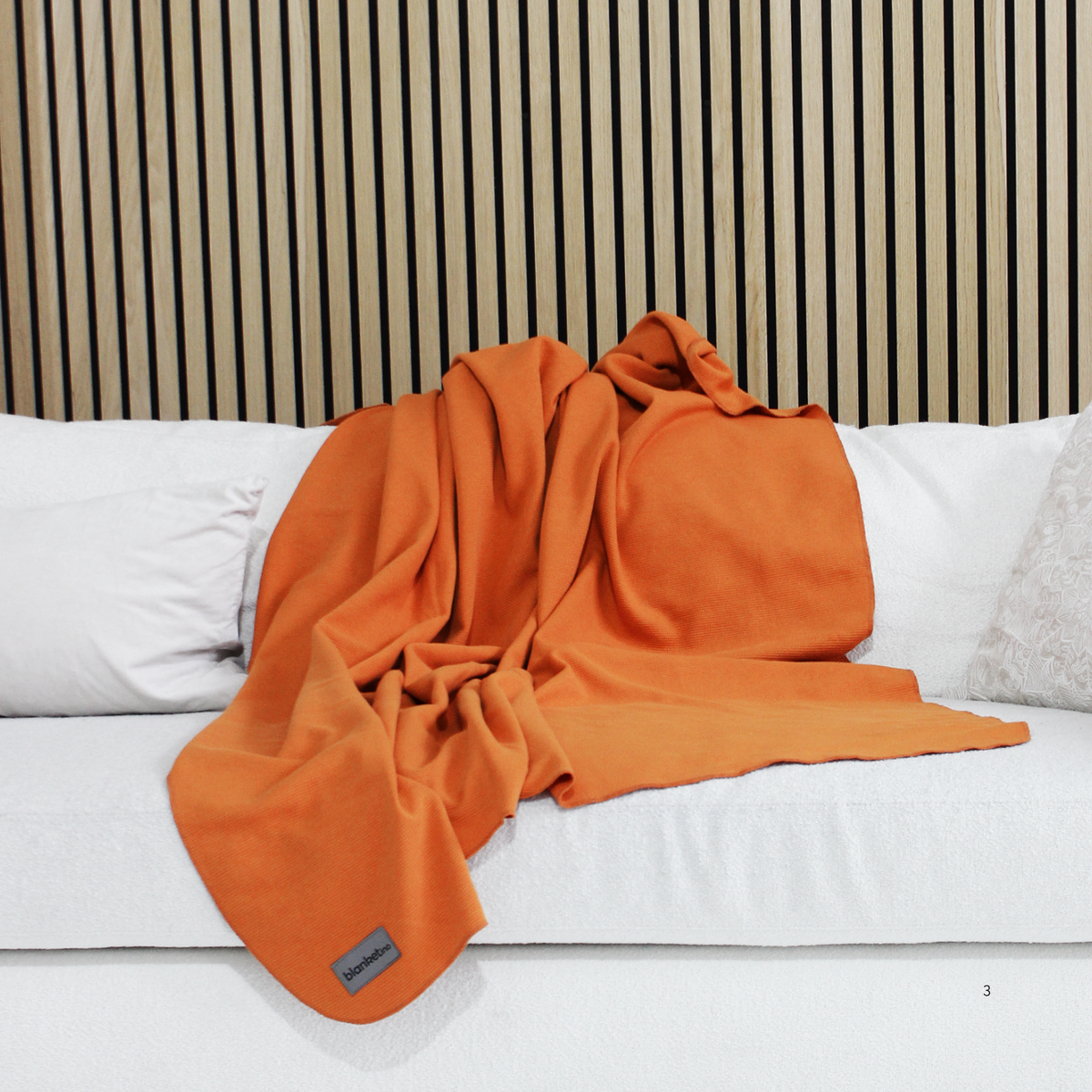 Leichte Baumwoll-Sommerdecke in Orange, 150 x 210 cm, auf einem weißen Sofa, von blanketino.de, mit intensiven Farbtönen