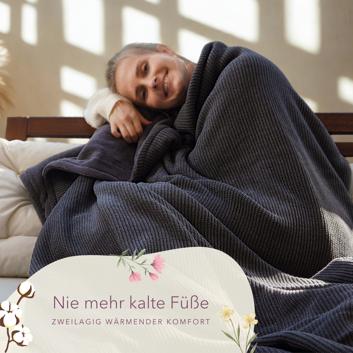 Dunkelgraue Kuscheldecke mit Baumwollstrick von blanketino.de, eine Frau eingekuschelt, angenehm weich und warm.