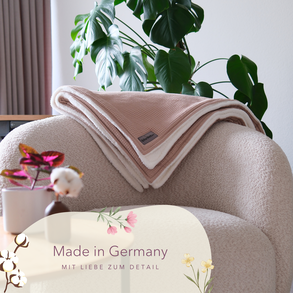 Kuscheldecke „Vollkommen“ von blanketino.de in Latte Macchiato Waffelpique, gefaltet auf hellem Sessel, weiches und warmes Textil.