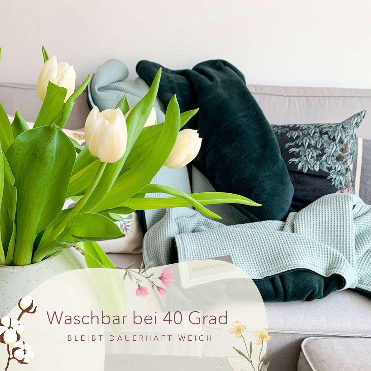 Weiche Kuscheldecke "Vollkommen" in Mint und Smaragdgrün, aus Waffelpique, auf Sofa mit Tulpen sichtbar