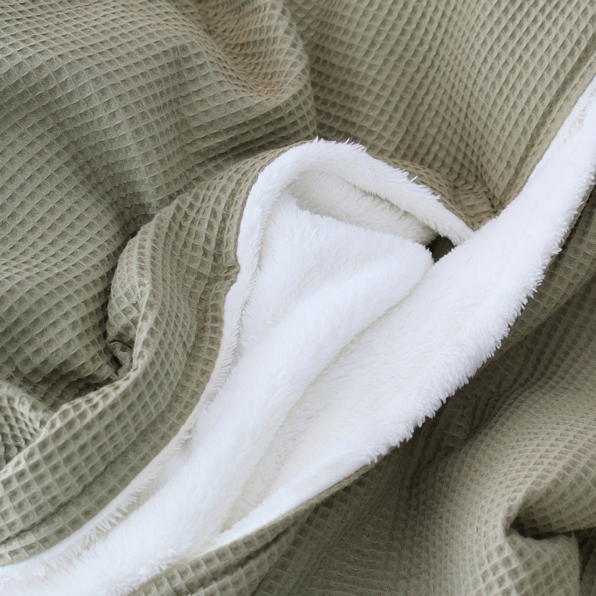 Weiche Kuscheldecke "Vollkommen" in Oliv mit Waffelpique-Design und weißer Rückseite, von blanketino.de.