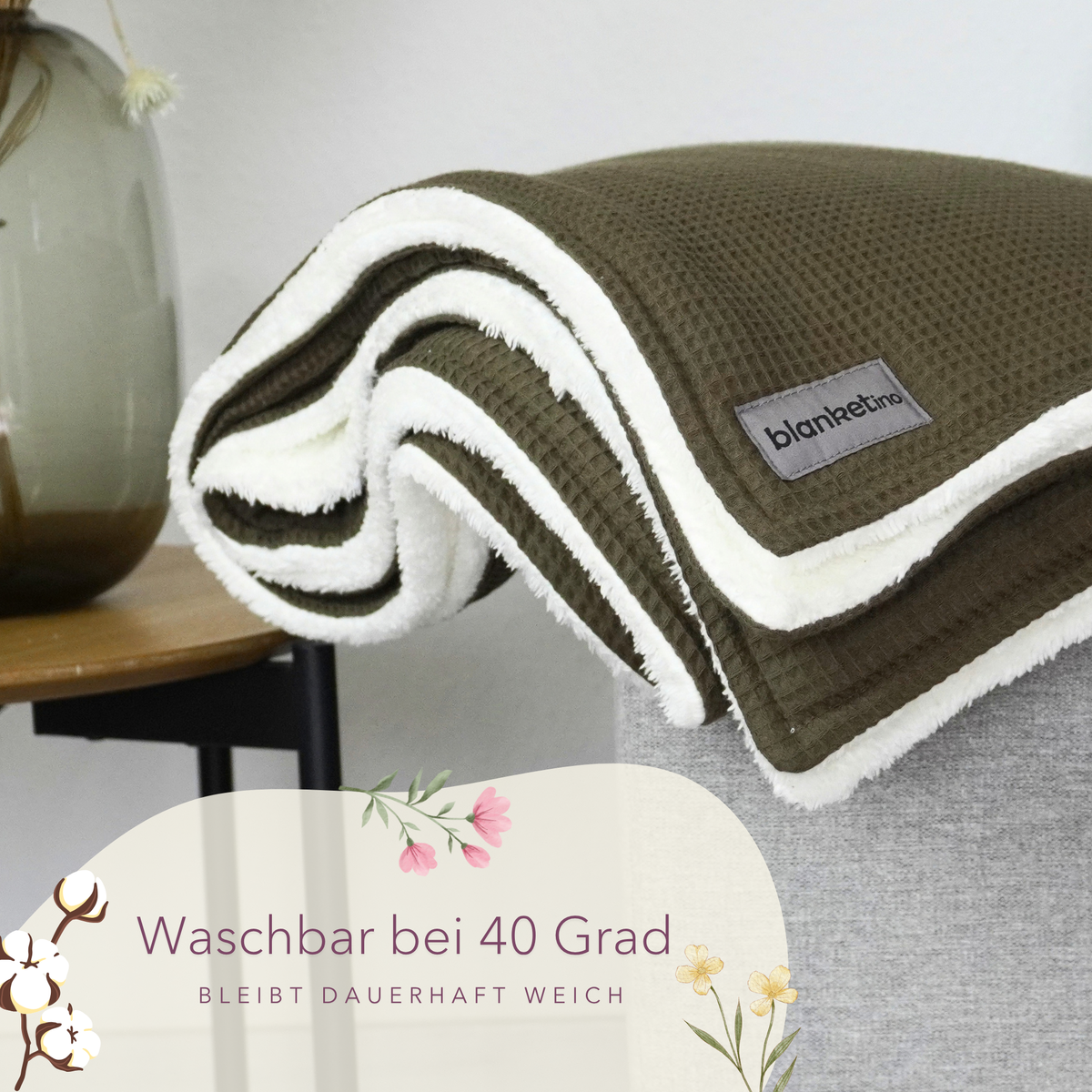 Waldgrüne Kuscheldecke "Vollkommen" von blanketino.de, gefaltet auf Sofa, weicher Waffelpique, waschbar, gemütliches Wohnaccessoire